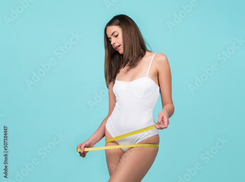 Slim girl holding a centimeter around the buttocks. Slim young woman measuring her butt with a tape measure, weight los. © Volodymyr