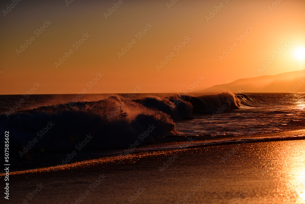 Waves splashes. Sunset over sea with golden dramatic sky panorama. Ocean and sky background. Ocean waves background.
