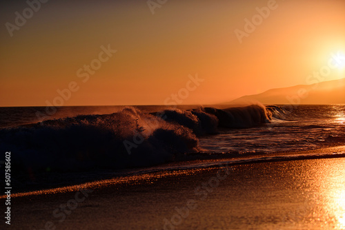 Waves splashes. Sunset over sea with golden dramatic sky panorama. Ocean and sky background. Ocean waves background.
