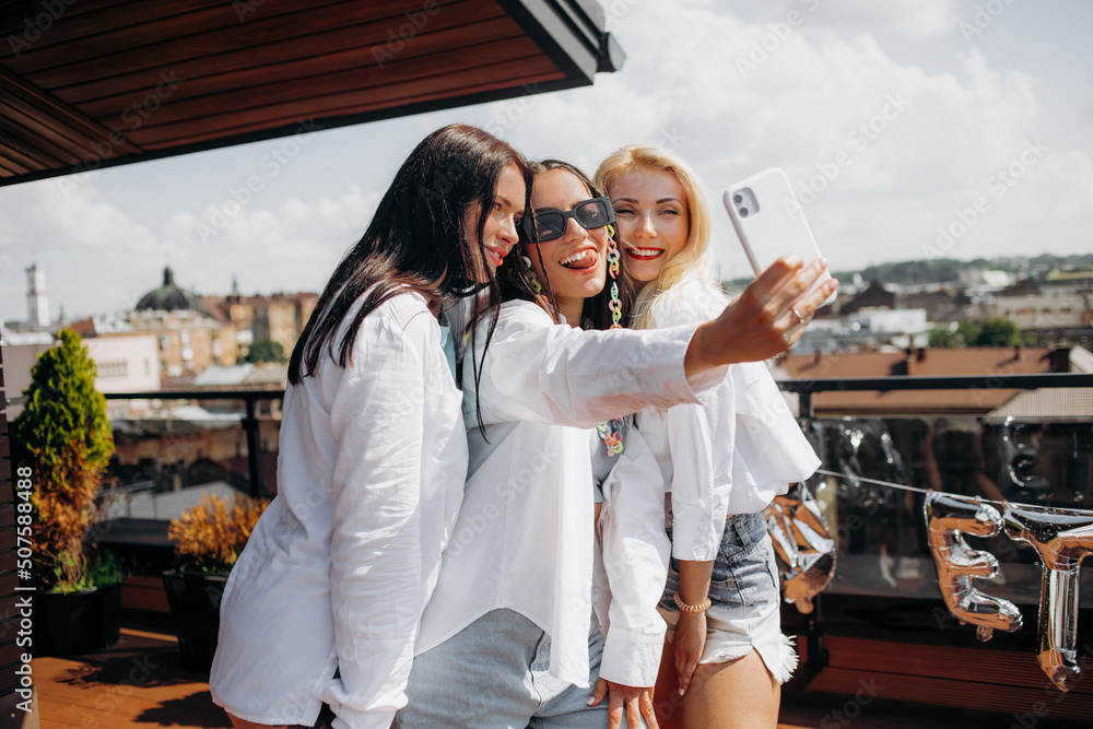 Happy and cheerful group of women friends together dancing and having fun  on the rooftop at home. Bachelorette party. Photos | Adobe Stock