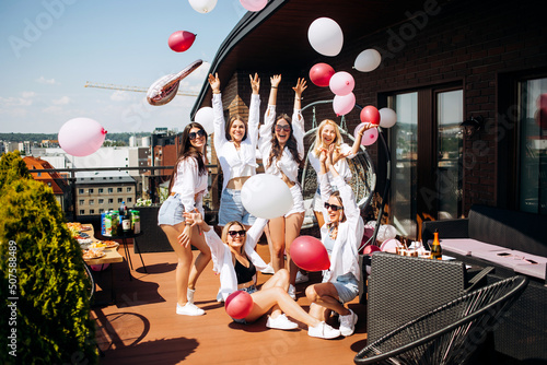 Happy and cheerful group of women friends together dancing and having fun on the rooftop at home. Bachelorette party.