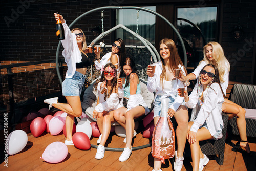 Happy and cheerful group of women friends together dancing and drink champagne on the rooftop at home. Bachelorette party.