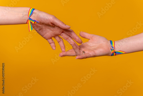 Hands of two women caressing and touching fingers, LGBT concept on a yellow background, couple of lesbian girls