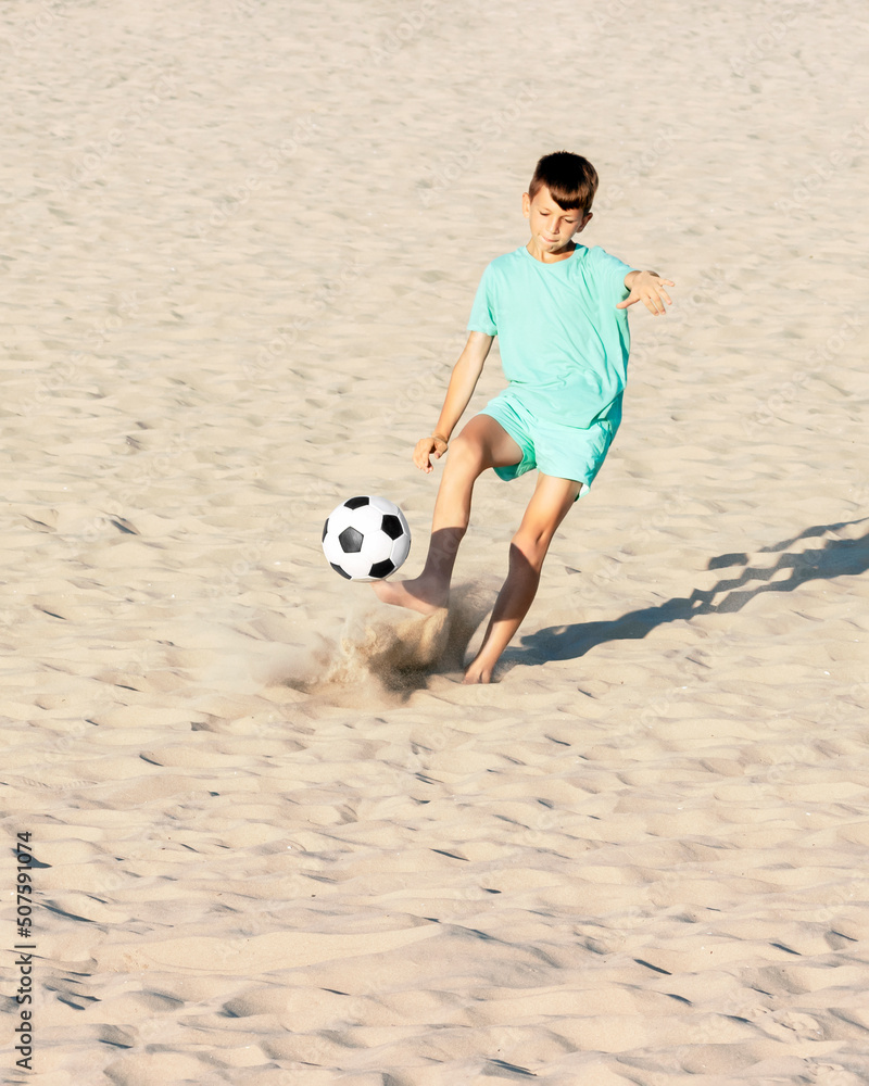 Young soccer player kicks football ball with his bare feet on beach on sea  sand. Beach soccer, summer holidays, sport games outdoor concept Stock  Photo | Adobe Stock