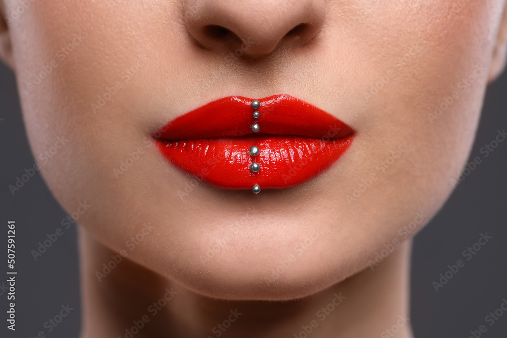 Obraz premium Young woman with red lips makeup on grey background, closeup