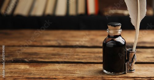 Quill and bottle of ink on wooden table, space for text. Banner design