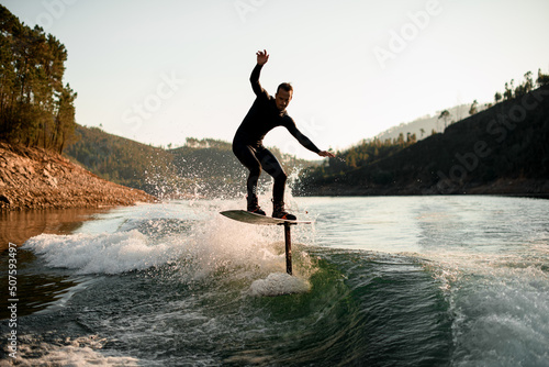 Tablou canvas athletic man skillfully balances on splashing wave on a foil wakeboard
