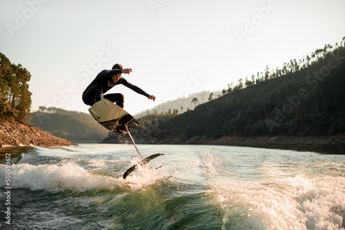 young active man jump with foil wakeboard over splashing wave © fesenko