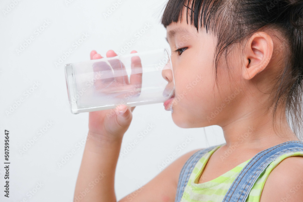 Cute little girl drinking milk from a glass isolated on white background. Little girls enjoy drinking milk before going to school. Cute little girl drinking milk from a glass isolated on white background. Little girls enjoy drinking milk before going to school.