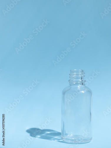 Small empty glass bottle on a blue background. vertically. Place for text.