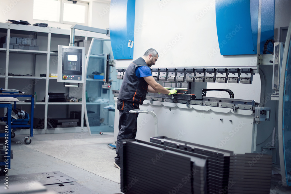 Fototapeta premium A smart factory worker or engineer makes machines in a production workshop. The concept of industry and engineering. Selective focus