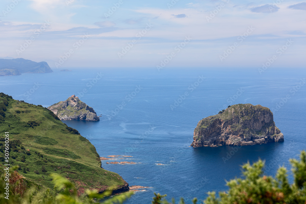 Picturesque emerald Basque coast along Bay of Biscay with rocky islands on shelf and piercing blue water of Bay of Biscay. Cabo Matxitxako, Biscay, Basque Country, Spain Picturesque emerald Basque coast along Bay of Biscay with rocky islands on shelf and piercing blue water of Bay of Biscay. Cabo Matxitxako, Biscay, Basque Country, Spain