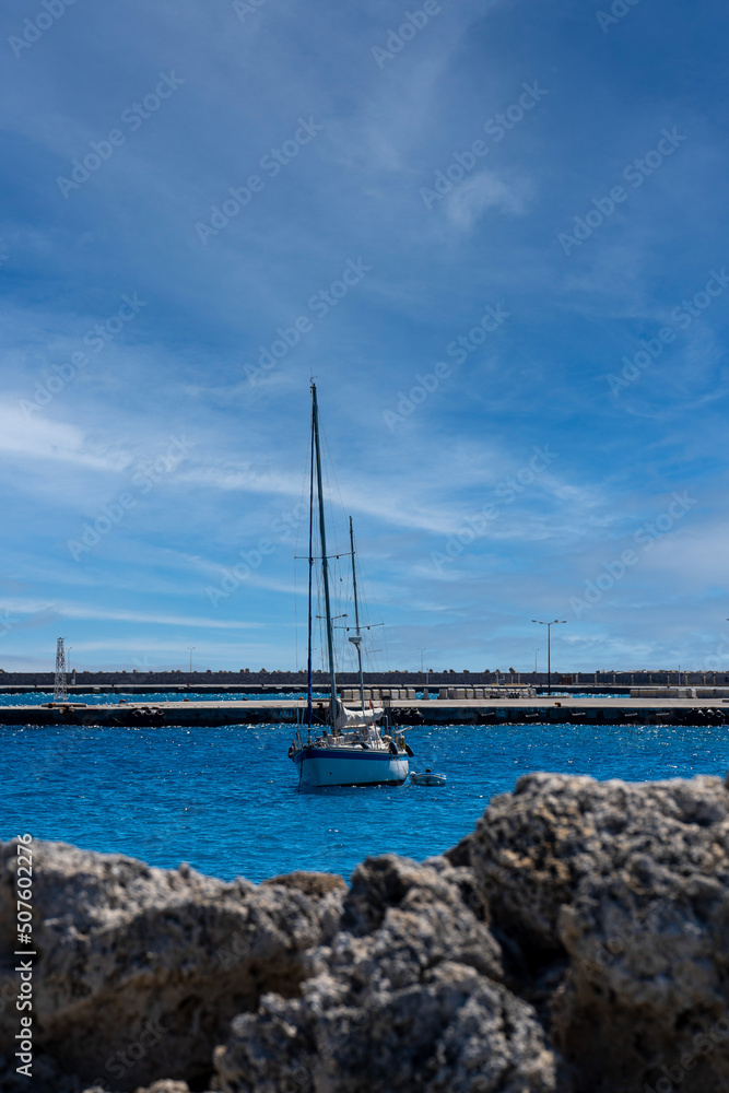 Obraz premium Sailing yacht view behind rocks in day light.