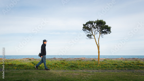 Man walking along Napier Marine Parade seafront, Hawke’s Bay, New Zealand.