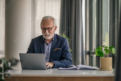 Senior businessman using laptop while working at desk in office