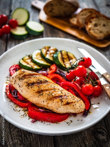 Grilled chicken breast with pepper, zucchini and cherry tomatoes on wooden table 