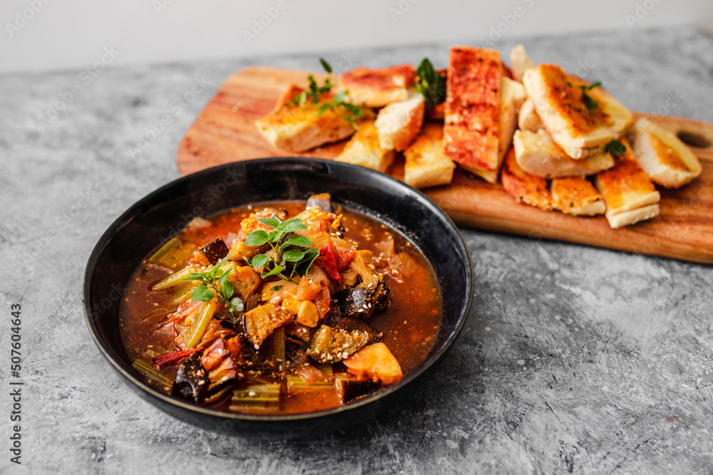 healthy plant-based food, vegan turkish güveç hot pot with eggplant celeri and potaotes in spicy broth with garlic bread healthy plant-based food, vegan turkish güveç hot pot with eggplant celeri and potaotes in spicy broth with garlic bread