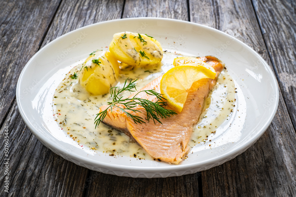 Roasted trout fillet with potatoes and dill sauce served on wooden table
Roasted trout fillet with potatoes and dill sauce served on wooden table
