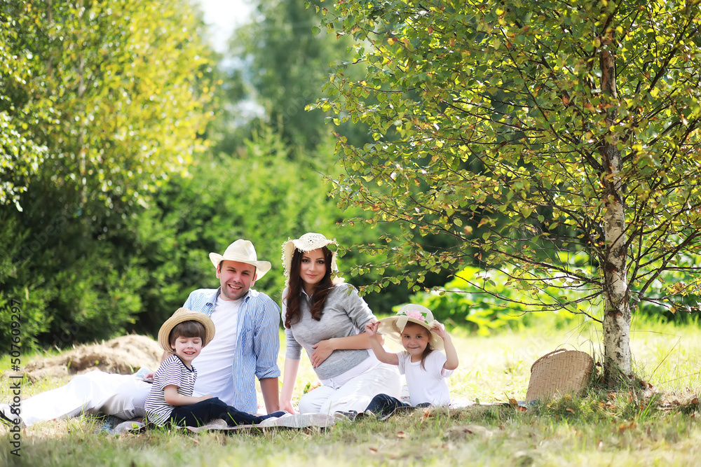 Happy family with children having picnic in park, parents with kids sitting on garden grass and eating watermelon outdoors Happy family with children having picnic in park, parents with kids sitting on garden grass and eating watermelon outdoors
