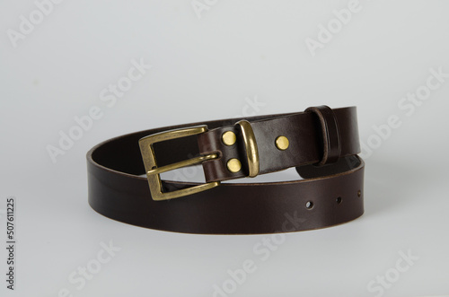 brown Italian leather belt with brass buckle and brass screws on a light background