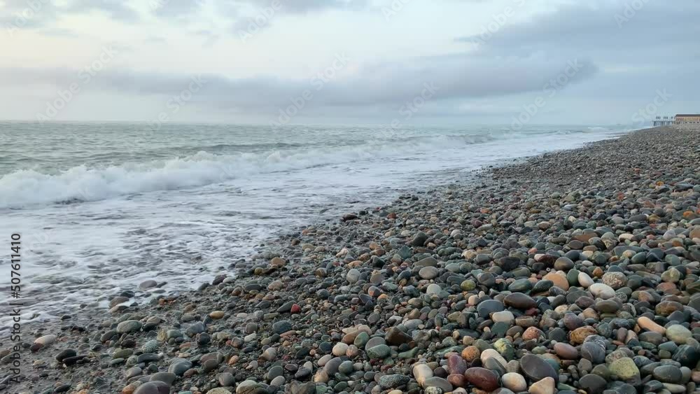 Coast of stones. Tide waves. Sea beach gray day. Wind Nature without man. Marine background place for text. Close up of water waves. Volumetric white clouds in sky. Beach for relax in winter autumn. Coast of stones. Tide waves. Sea beach gray day. Wind Nature without man. Marine background place for text. Close up of water waves. Volumetric white clouds in sky. Beach for relax in winter autumn.