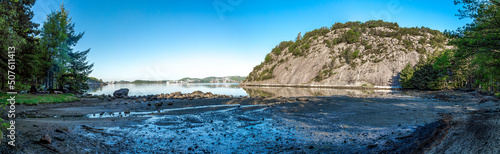 Panorama of a small rocky beach of Gandsfjord fjord near Dale with a tourist setting a campfire, Sandnes, Norway, May 2018