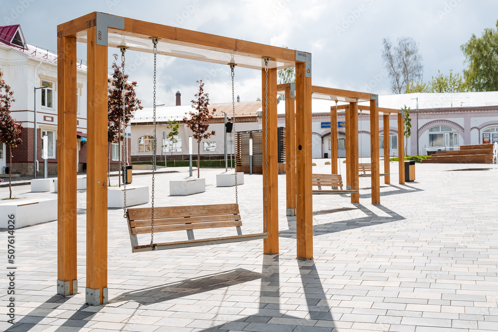 Outdoor swings of modern design, a town square, a place of rest for citizens, wooden benches, swinging on chains, an amusement park. Outdoor swings of modern design, a town square, a place of rest for citizens, wooden benches, swinging on chains, an amusement park.