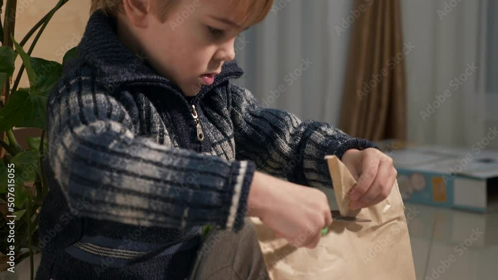 Child Cut with Scissors Opens Package with Toy Details. Kid Unboxing Present at Home. 2x Slow motion 4K 60fps Child Cut with Scissors Opens Package with Toy Details. Kid Unboxing Present at Home. 2x Slow motion 4K 60fps