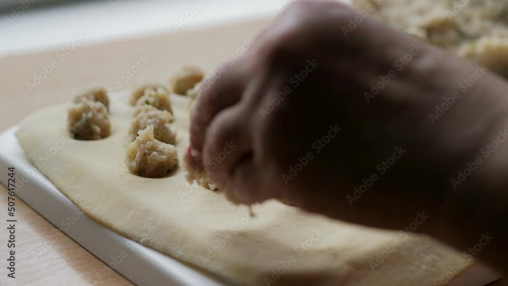 Close-Up Of Female Hands Making Dumplings With Minced Meat. With our hands, we spread the meat filling into the dough, a form for dumplings. Traditional Russian cuisine. Cooking homemade food.Ravioli Close-Up Of Female Hands Making Dumplings With Minced Meat. With our hands, we spread the meat filling into the dough, a form for dumplings. Traditional Russian cuisine. Cooking homemade food.Ravioli