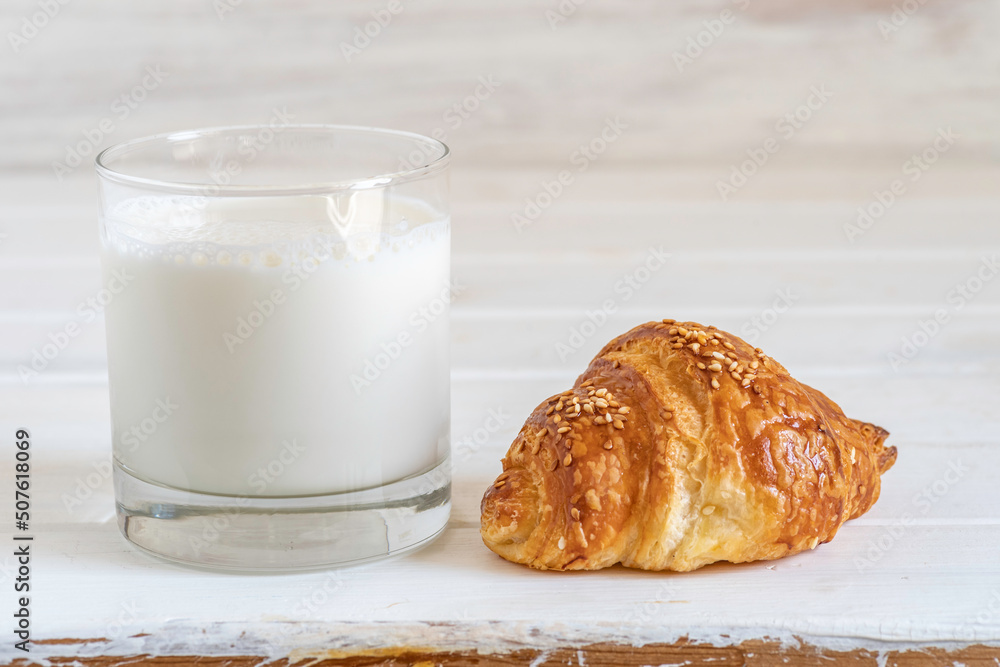 Sweet croissant and glass of milk on white wooden background. Sweet croissant and glass of milk on white wooden background.