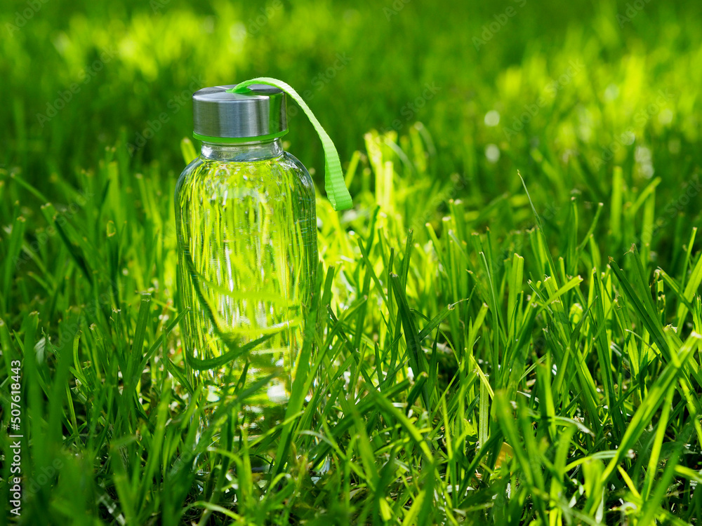 Glass bottle with water on grass background Glass bottle with water on grass background