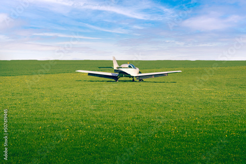 A small plane takes off from a grassy airport.