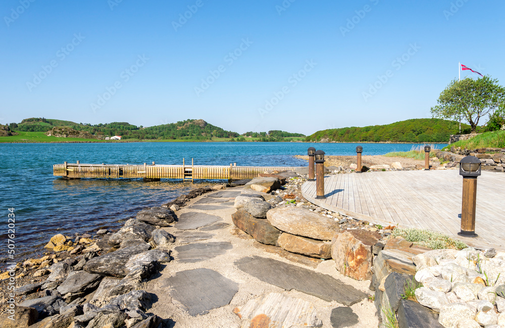 A stone footpath and a small wooden jetty in Hafrsfjord residential suburb, Stavanger, Norway, May 2018