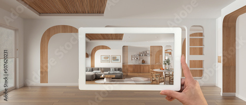 Augmented reality concept. Hand holding tablet with AR application used to simulate furniture and design products in panoramic empty interior, living room, dining room and kitchen