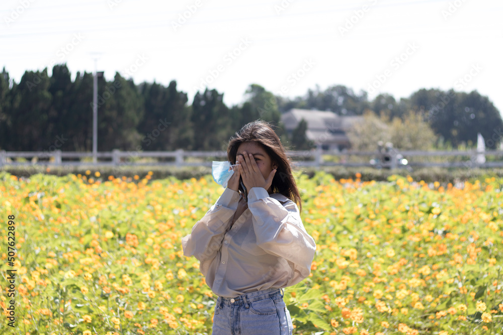 Closeup Portrait of a beautiful young girl with enjoying nature outdoors and sky, on a beautiful yellow cosmos flower field, beautiful young woman face closeup.