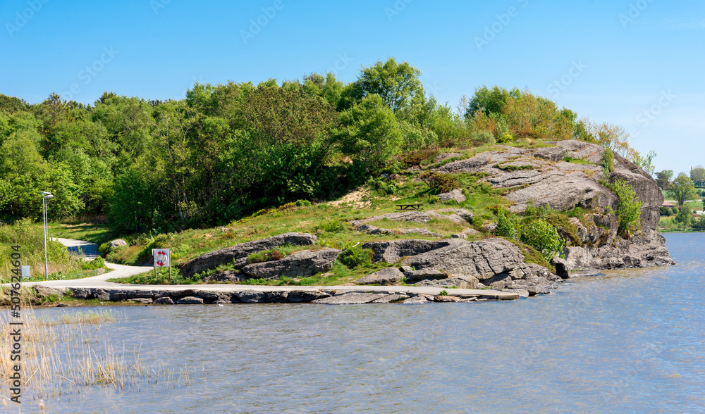A scenic viewpoint hill with a bench on a slope and a footpath around Halandsvatnet lake, Stavanger, Norway, May 2018