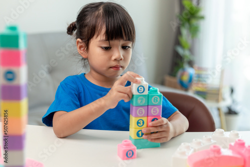 Adorable little girl playing toy blocks in a bright room