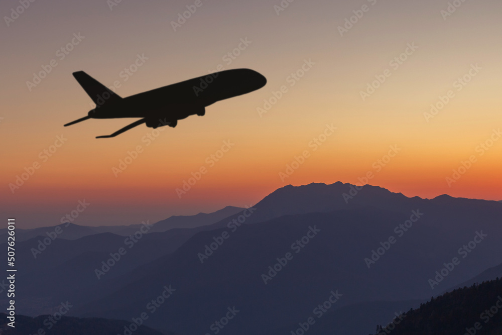 Fototapeta premium silhouette of the plane flies over the mountains at sunset,beautiful landscape,nature,travel and air tickets background
