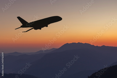 silhouette of the plane flies over the mountains at sunset,beautiful landscape,nature,travel and air tickets background