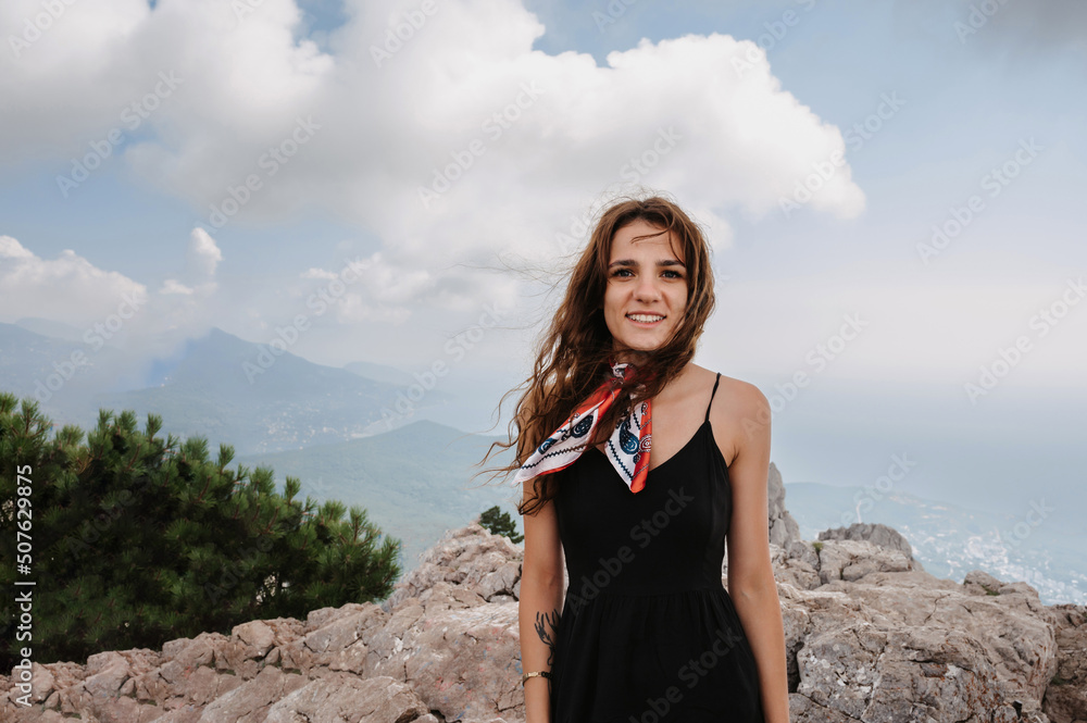 Naklejka premium A young fearless woman poses after crossing a rope bridge over a precipice high in the mountains.