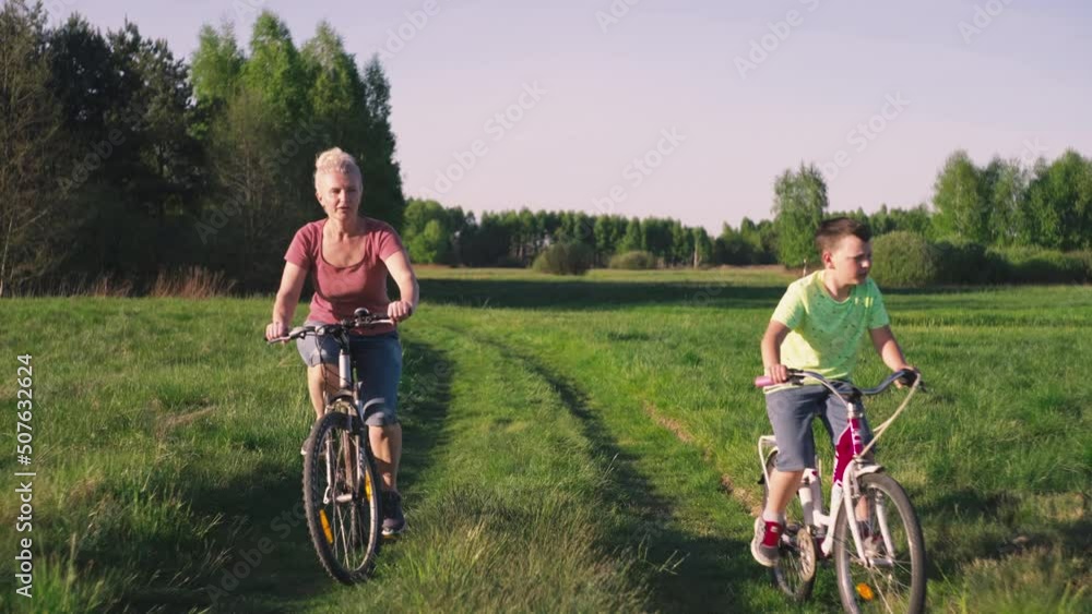 Mom and baby ride a bicycle across the field. Beautiful nature and the family is engaged in sports and recreation in the park. Mom and baby ride a bicycle across the field. Beautiful nature and the family is engaged in sports and recreation in the park.