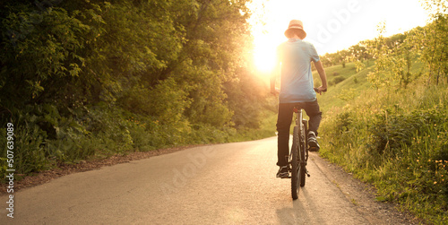 Fototapet teenager riding a bicycle on the road summer sunlit