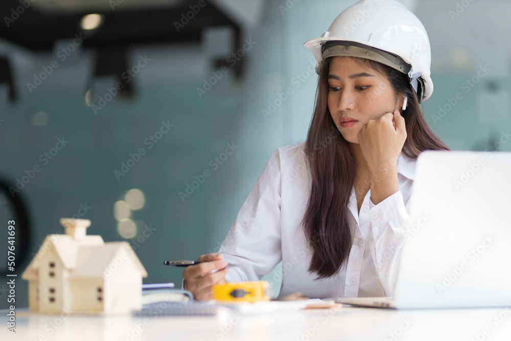 Female architect designer in an office working on a laptop is modeling a house and writing a housing project. Female architect designer in an office working on a laptop is modeling a house and writing a housing project.