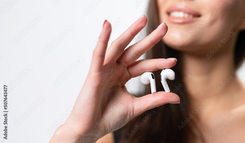 Headphones holding in woman hands. Wireless earbuds focused closeup. Headphones holding in woman hands. Wireless earbuds focused closeup.