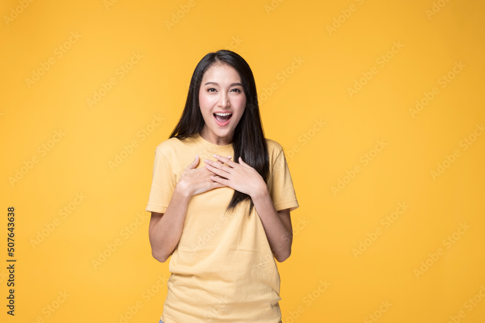Young Asian Woman making Hand gesture with Surprise Face. Happy Asian Woman wearing Yellow T-shirt standing over yellow background. Portrait of Happy Asian female. Young Asian Woman making Hand gesture with Surprise Face. Happy Asian Woman wearing Yellow T-shirt standing over yellow background. Portrait of Happy Asian female.
