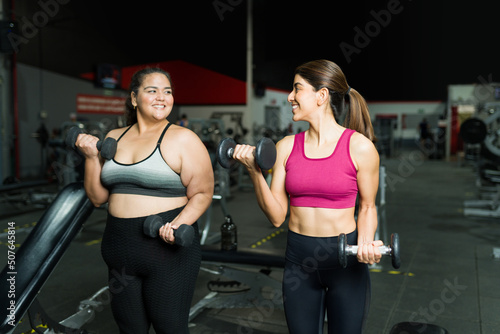 Smiling personal trainer and fat woman exercising