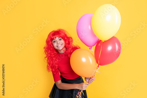 positive kid with party balloon on yellow background