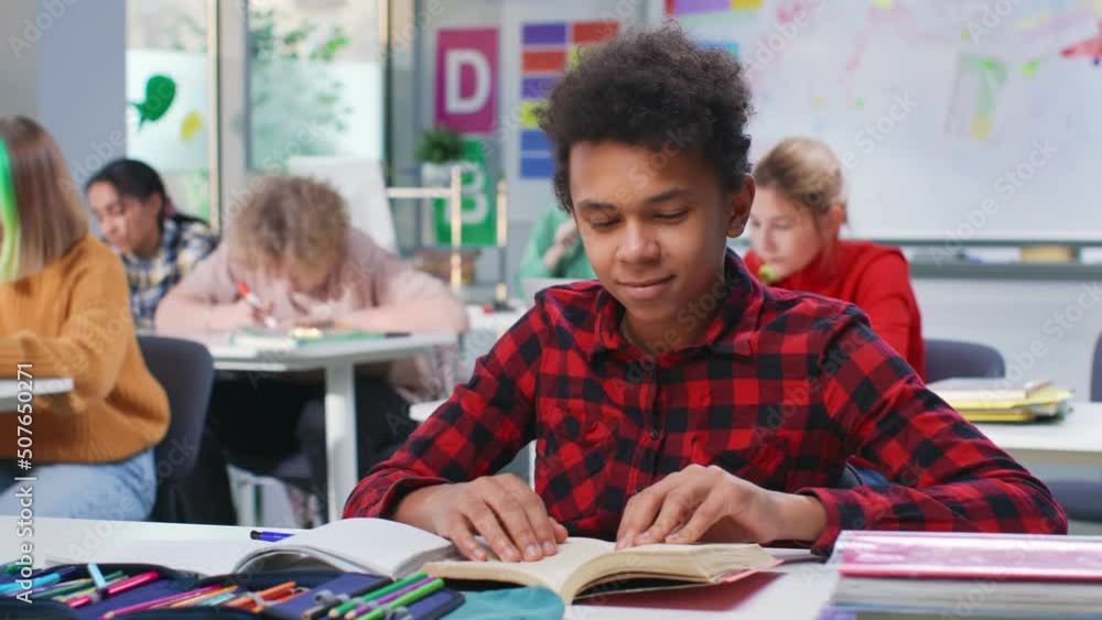 African-American teenage boy read book sitting at desk in classroom African-American teenage boy read book sitting at desk in classroom