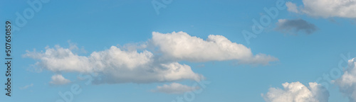 Banner with panoramic view over deep blue clean sky with illuminated clouds as a background.