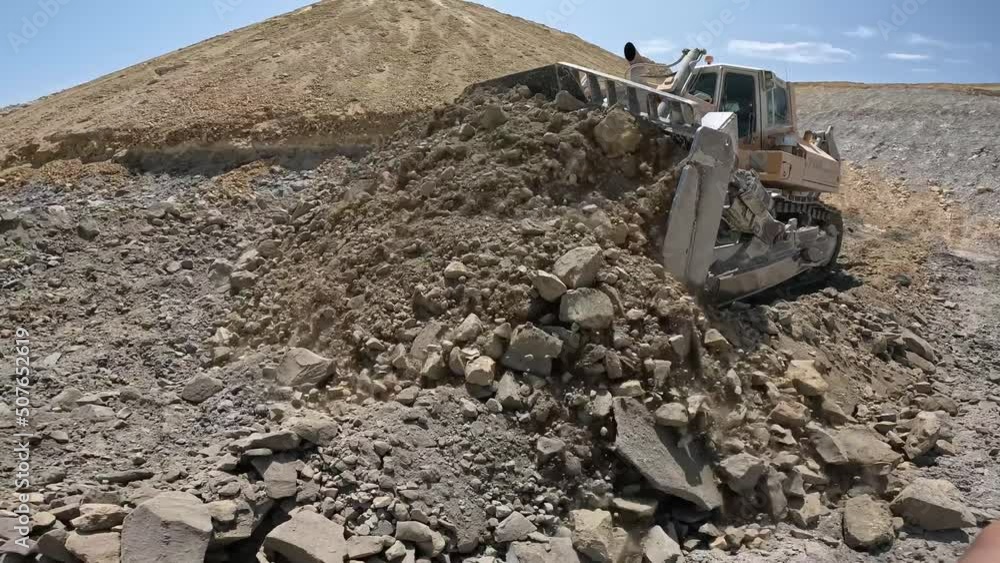 Bulldozer in operation while moving rocky material in the quarry 4K. Bulldozer in operation while moving rocky material in the quarry 4K.